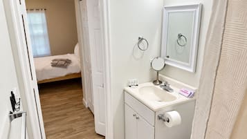 A bathroom with a sink, mirror, and toilet paper.