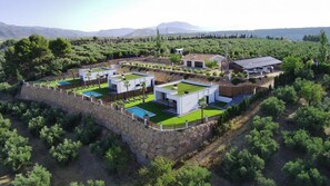 A modern villa with multiple swimming pools, surrounded by lush greenery and a stone wall. - Mirador el Llano 3 Pozo Alcón by Ruralidays (Province of Jaén)