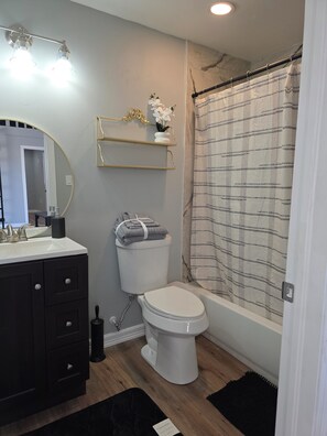 A bathroom with a toilet, sink, and shower curtain.