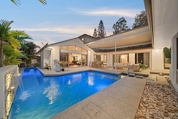 Una casa moderna con piscina, mobili da esterno e una zona patio.