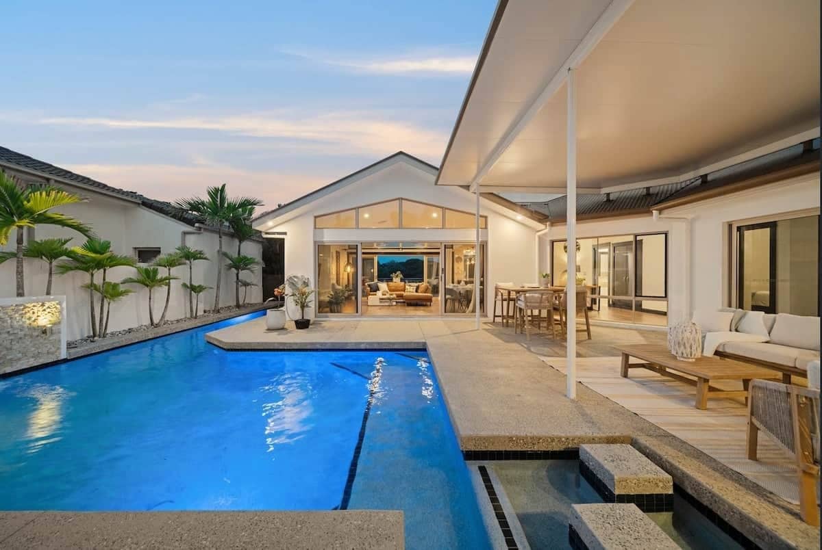 A modern house with a swimming pool, outdoor seating, and a covered patio area.