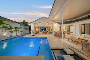 A modern house with a swimming pool, outdoor seating, and a covered patio area. - Waterfront 5BR + Pool | Kawana Island | Sleeps 10 (Parrearra)