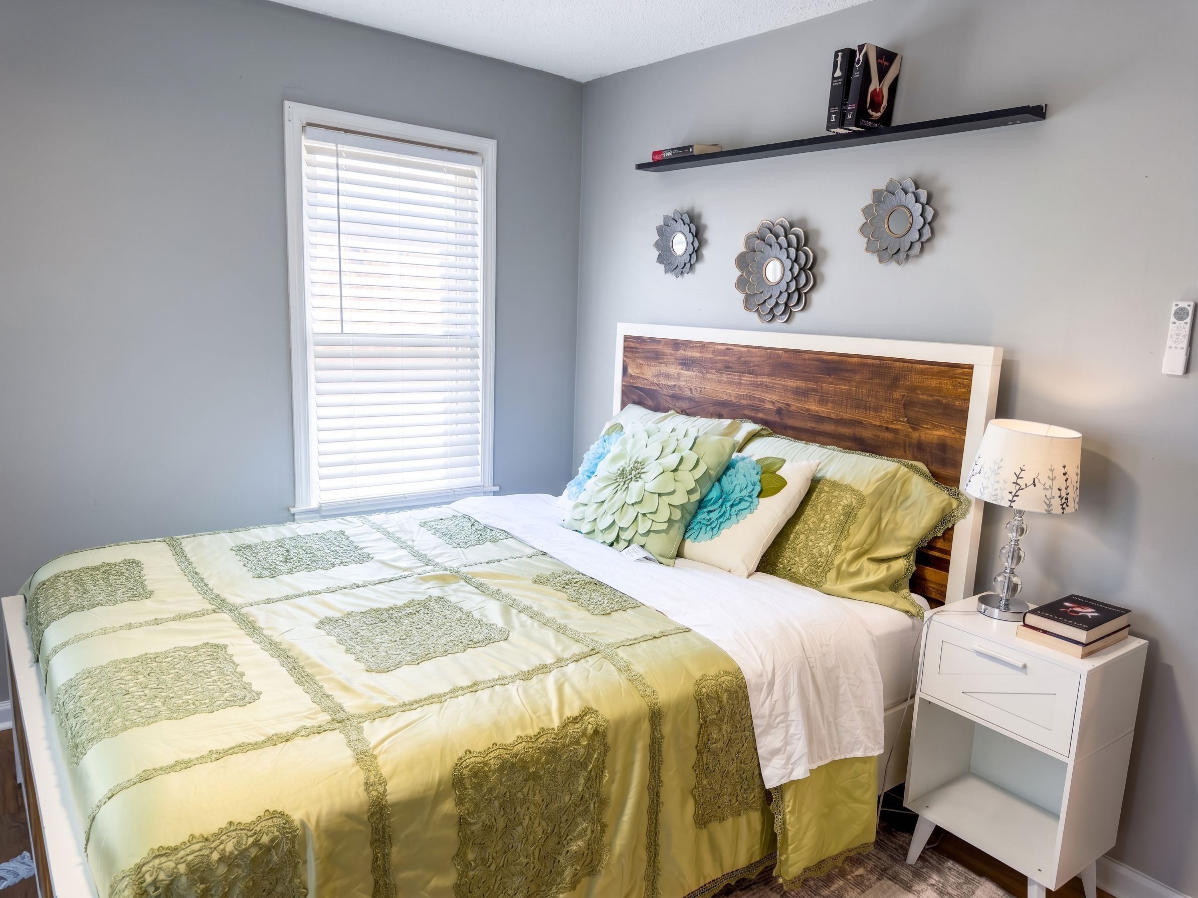A bedroom with a bed, a nightstand, a lamp, and decorative items on the wall.