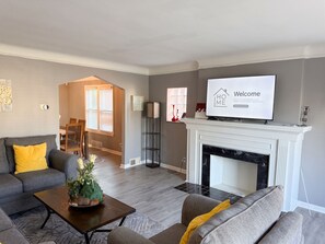 A living room with a fireplace, a television, and a dining area. - Large 4-bedroom townhome with AC walking distance from DMC Sinai Grace Hospital (Detroit)