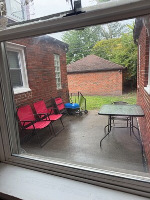 A patio with a table and chairs, a blue grill, and a brick building in the background. - Large 4-bedroom townhome with AC walking distance from DMC Sinai Grace Hospital (Detroit)