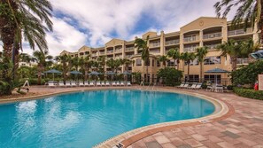 A hotel with a swimming pool, palm trees, and lounge chairs. - Oceanfront 2BR Villa at Cape Canaveral Beach Resort – Space & Sun (Cape Canaveral)
