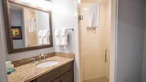 A bathroom with a sink, mirror, and shower. - Oceanfront 2BR Villa at Cape Canaveral Beach Resort – Space & Sun (Cape Canaveral)