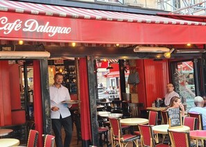 An outdoor café with a red awning and wicker chairs. - JUST MOMENTS FROM THE LOUVRE, OPÉRA GARNIER & GRANDS BOULEVARDS (Paris)