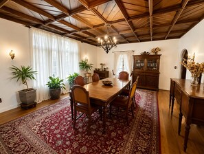 Ein Essbereich mit Holztisch, Stühlen, einer Deckenleuchte, Topfpflanzen und einem Schrank.