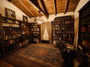 Une bibliothèque avec des étagères en bois, une moquette à motifs et un lustre.