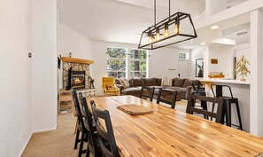 Ein geräumiger Essbereich mit Holztisch und -stühlen, einem Steinofen und einer modernen Pendelleuchte.