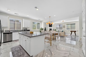 A modern kitchen with white cabinetry, a marble countertop, and a central island.
