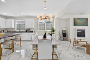 A modern kitchen with white cabinets, a marble countertop, and a central island with bar stools.