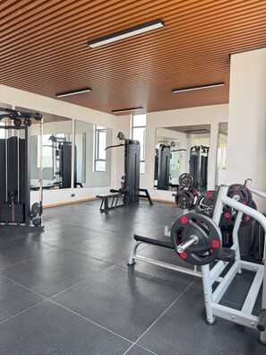 A gym with exercise equipment, mirrors, and a wooden ceiling. - 15th floor | Heart of Westlands | Skyline | Heated pool | Near GTC & Sarit (Nairobi)