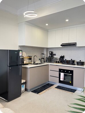 A modern kitchen with a built-in oven, a coffee maker, and a refrigerator. - 15th floor | Heart of Westlands | Skyline | Heated pool | Near GTC & Sarit (Nairobi)
