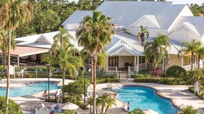 Un resort con piscina, palmeras y un patio techado.