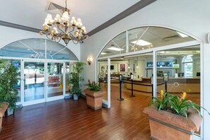 A lobby with a reception desk, glass doors leading outside, and potted plants. - No Resort Fees - 2-Acre Waterpark - Disney 9 Miles to Disney - Walk to dining (Davenport)