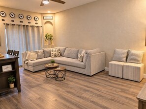 A living room with a sectional sofa, a small coffee table, a side table, and a dining area with a table and chairs. - No Resort Fees - 2-Acre Waterpark - Disney 9 Miles to Disney - Walk to dining (Davenport)