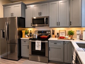 A modern kitchen with grey cabinets, stainless steel appliances, and a pasta-themed towel. - No Resort Fees - 2-Acre Waterpark - Disney 9 Miles to Disney - Walk to dining (Davenport)