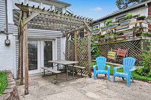 Une terrasse dotée d’une pergola en bois, d’une table de pique-nique et de deux chaises bleues.