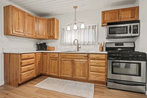 Une cuisine avec des meubles de rangement en bois, un évier, une machine à café, un four à micro-ondes et une cuisinière.