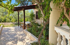 An outdoor patio with a pergola, stone wall, and potted plants. - Gorgeous apartment in Razanac with house sea view (Razanac)