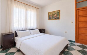 A bedroom with a bed, a nightstand, a painting on the wall, and a wooden door. - Gorgeous apartment in Razanac with house sea view (Razanac)