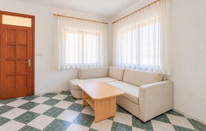 A room with a wooden door, a beige sofa, a small wooden table, and checkered floor tiles. - Gorgeous apartment in Razanac with house sea view (Razanac)