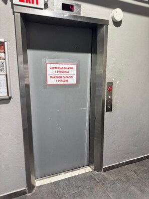 Eine Aufzugtür mit einem Schild, das eine maximale Personenzahl von 4 angibt.