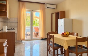 Ein Hotelzimmer mit Essbereich, einer Küche und einem Balkon mit Vorhängen.