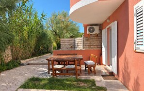 Un patio con una mesa y sillas de madera, un muro de ladrillo y una ventana con persianas.