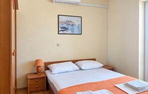 A hotel room with a bed, a nightstand, a lamp, a framed picture on the wall, and a window. - Stunning apartment in Razanac with house sea view (Razanac)
