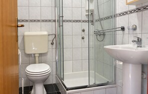 Ein Badezimmer mit Toilette, einer Duschkabine aus Glas und einem Waschbecken.