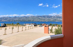 A coastal view with a clear sky, a parking area, and a mountainous backdrop. - Nice apartment in Razanac with WiFi (Razanac)