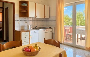 A kitchen with a dining table, chairs, and a fruit basket. - Cozy apartment in Razanac with WiFi (Razanac)