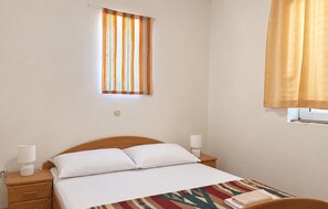 A hotel room with a bed, bedside lamps, a window with curtains, and a wall socket. - Cozy apartment in Razanac with WiFi (Razanac)
