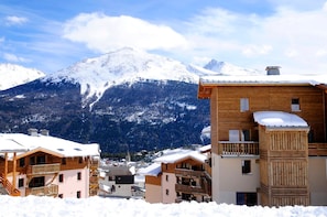 A snow-covered mountain town with wooden buildings and a clear sky. - Au pied des pistes | Piscine intérieure chauffée (Aussois)