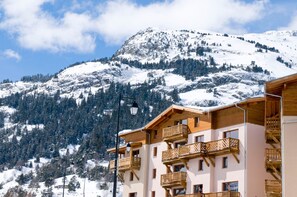 Eine Berglodge mit Holzbalkonen und Blick auf schneebedeckte Berge.