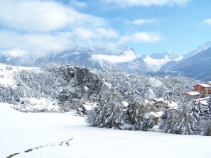 Un villaggio montano innevato con edifici tradizionali e cielo sereno.
