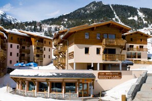 A mountain resort with wooden buildings, a reception area, and a sign for 'LES BOUQUETINS RESTAURANT BAR PIZZERIA CREPERIE.' - Au pied des pistes | Piscine chauffée | Balcon (Aussois)
