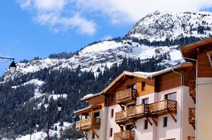 Eine Berglodge mit Holzbalkonen und Blick auf verschneite Hänge.