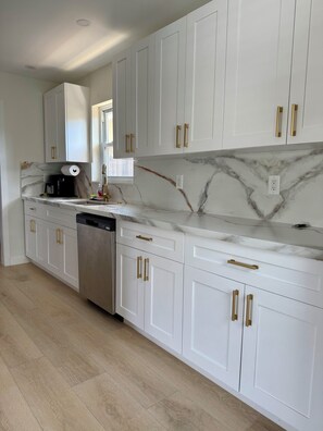 A modern kitchen with white cabinets, marble backsplash, and stainless steel appliances. - Spacious House W/Deck - Near FLL Airport, Beach, Dania Pointe & Hard Rock (Dania Beach)