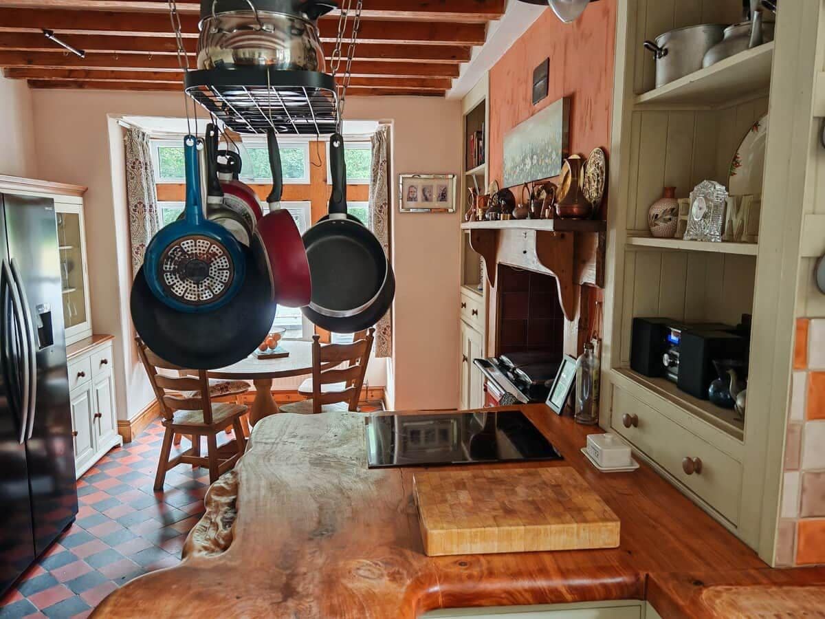A kitchen with wooden cabinets, a dining table, and hanging pots.