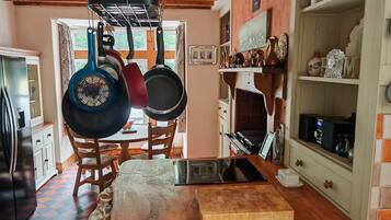 A kitchen with wooden cabinets, a dining table, and hanging pots.