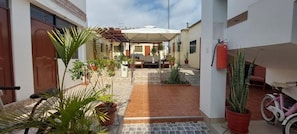 A covered outdoor seating area with a table and chairs, surrounded by potted plants and a fire extinguisher. - R. A. C. S. (Paracas-Paracas,)