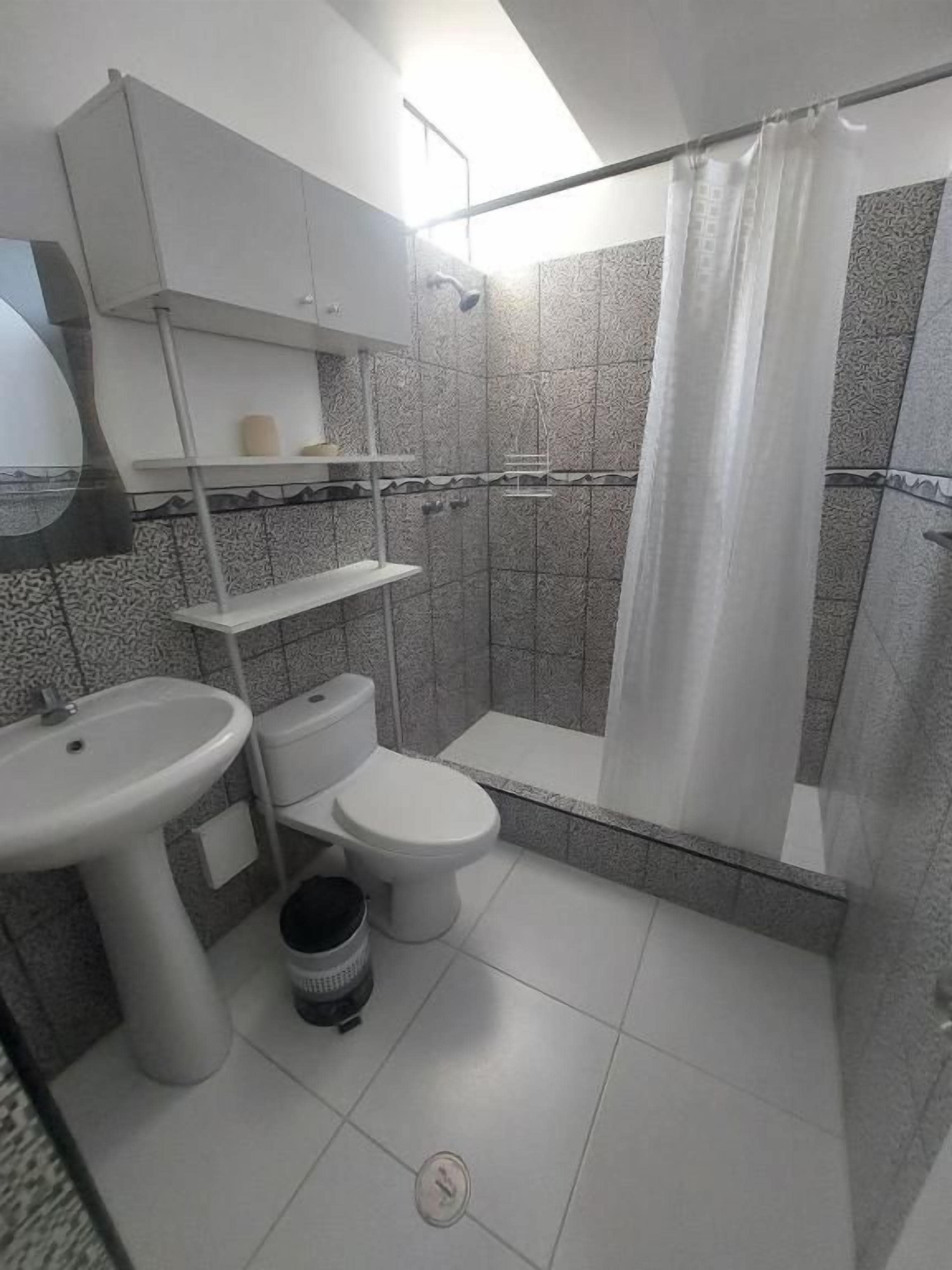 A bathroom with a toilet, sink, and shower.