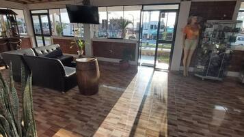 A spacious lobby with a leather sofa, a wooden barrel, and a large window offering a view of the street.