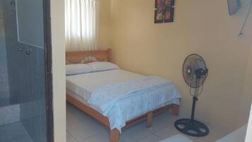 Un dormitorio con cama, ventilador y una silla.
