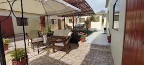An outdoor patio area with a covered seating area, potted plants, and a tiled floor. - R. A. C. S. (Paracas-Paracas,)