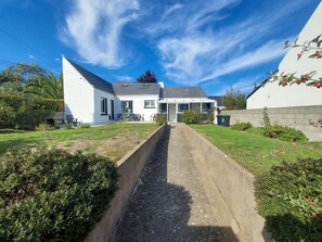 Ein Wohnhaus mit gepflasterter Auffahrt, das ein Satteldach und eine Veranda hat.
